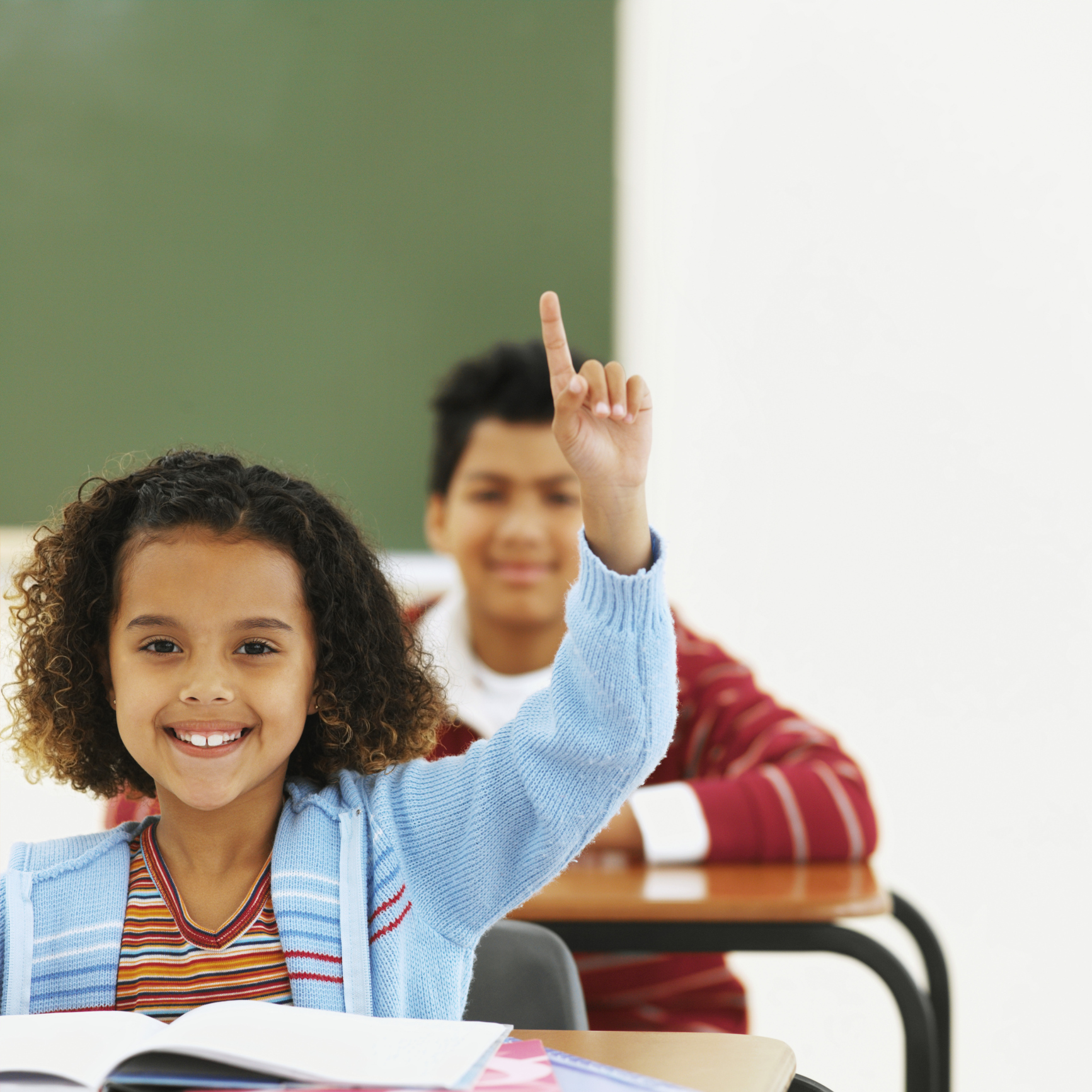 smiling girl in blue cardigan raising hand