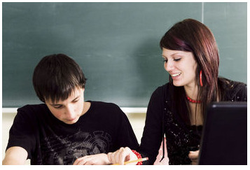 Tutor Helping Student in Front of Blackboard